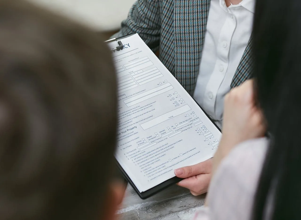 Dues persones repassen juntes l'imprès d'una pòlissa subjecte a un portapapers