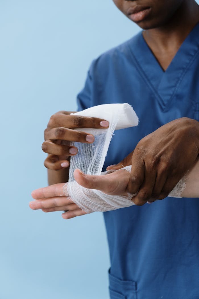 A healthcare professional wrapping a patient's hand with gauze for injury care.