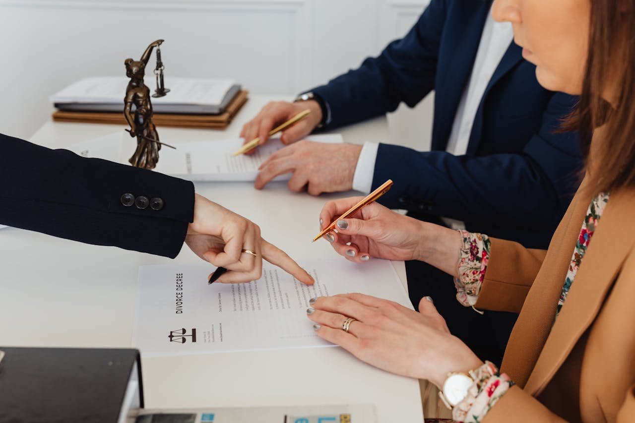 home-hero Hands signing a divorce decree, with a justice statue nearby, symbolizing legal proceedings.