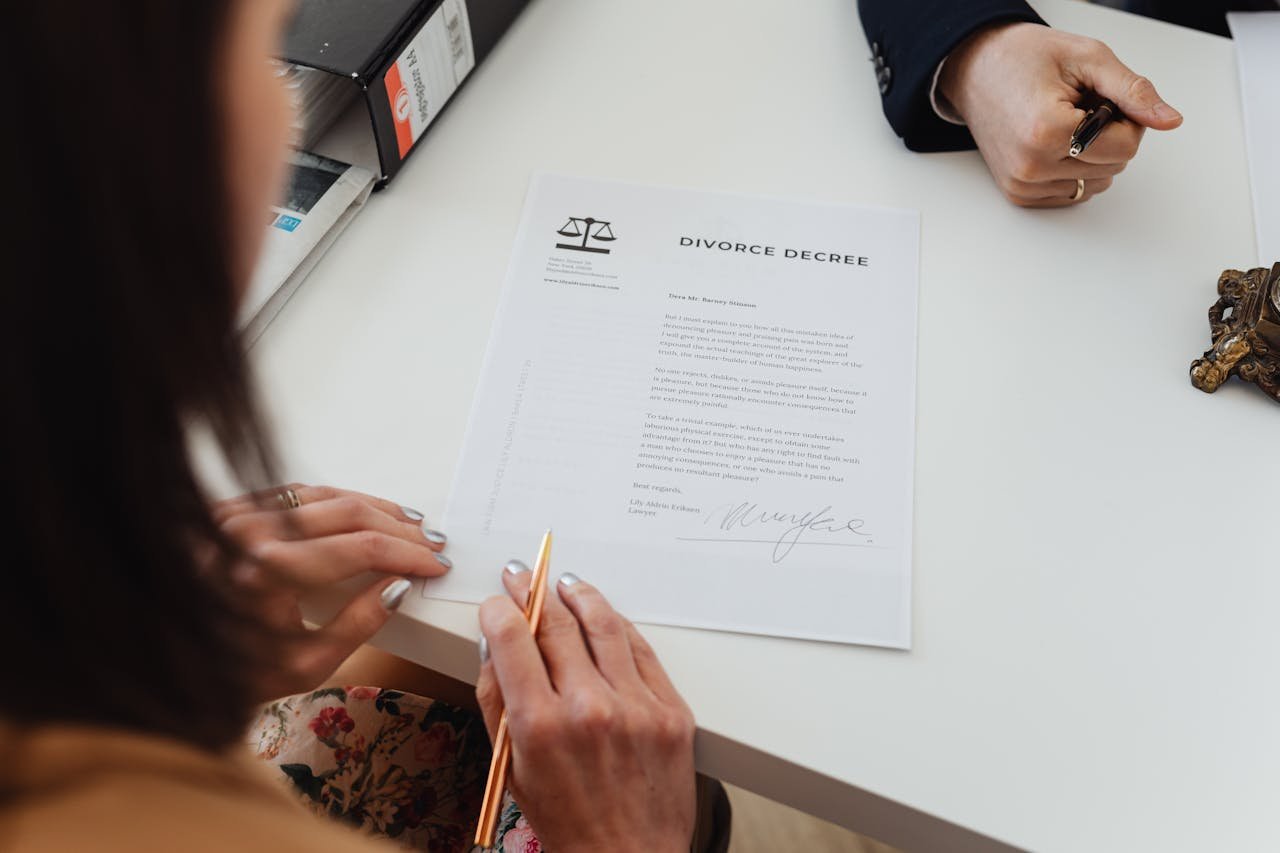 who-we-are A close-up shot of two people signing a divorce decree at a law office table.